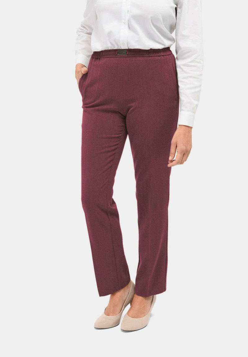 Pantalon bordeaux avec une finition texturée, taille élastique et poches latérales, associé à une chemise blanche et des talons beiges.