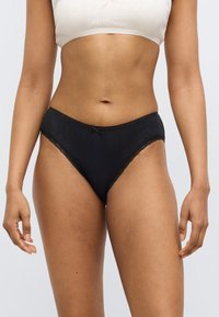Μαύρα μπικίνι σλιπ με δαντέλα στο τελείωμα και απαλή υφή, διακοσμημένα με διακριτικό μοτίβο και κεντρικό φιόγκο. Κατασκευασμένα από μαλακό ύφασμα.