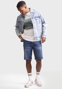 Light blue denim jacket, white t-shirt with striped pattern, dark blue denim shorts, white socks with black stripes, and silver sneakers.