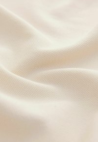 Lichtbeige textiel met een subtiel ruitpatroon, een gladde textuur en een zachte val, die een fijne weving en ademende kwaliteit toont.