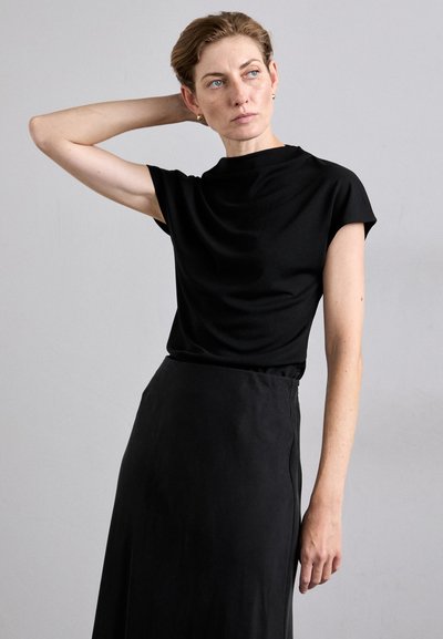 Black, short-sleeve top with high neck and smooth texture, paired with a long black skirt featuring a fitted waist and subtle side seam detail.