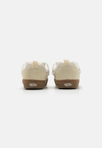 Beige suede and mesh sneakers with a brown rubber sole and Vans logo. Features a heel tab for easy wear and rounded toe design.