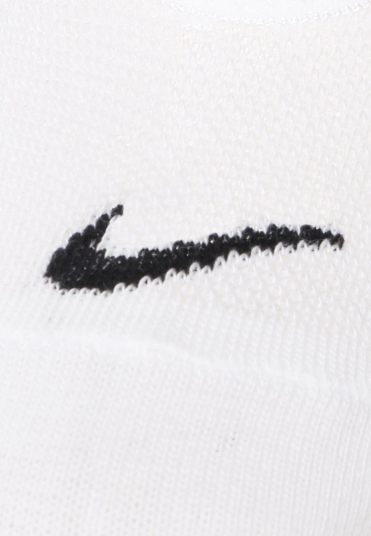Chaussette de sport blanche avec un tricot texturé. Présente un logo Nike en noir bien visible sur le côté extérieur.