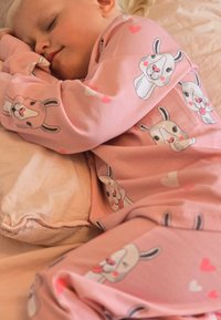 Pink pajama set with playful bunny faces and heart patterns, made of soft fabric, featuring long sleeves and matching pants.
