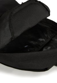 Svart ryggsäckinsida med en mjuk fodring och ett subtilt rutmönster, utrustad med ett vadderat fack och blixtlåsförslutning.