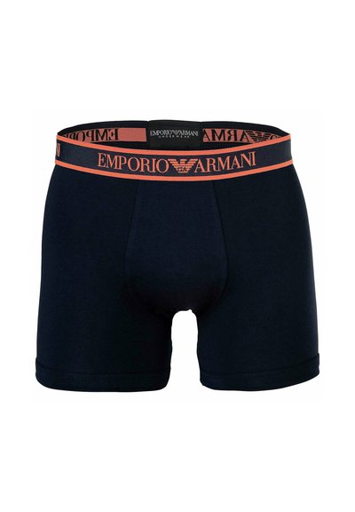 Schwarze Boxershorts mit orangefarbenem Markenbund, der das Emporio Armani-Logo und den Schriftzug zeigt, auf weißem Hintergrund zentriert.