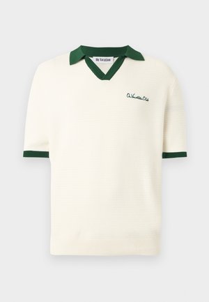 Bela kratka pletena polo majica s kratkimi rokavi, temno zelenim ovratnikom, robovi rokavov in vezenim napisom "On Vacation Club" na prsih.