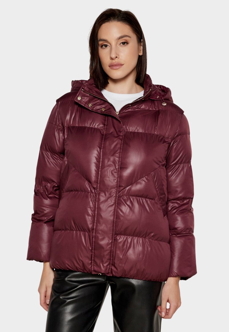 Giacca imbottita color bordeaux con cappuccio, texture trapuntata lucida e cuciture geometriche. Presenta una chiusura frontale con zip e doppi bottoni a pressione.