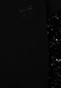 Maglione nero caratterizzato da un tessuto testurizzato con un dettaglio di ricamo a nastro a sinistra e accenti di paillettes a destra.