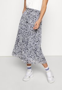 Květinová midi sukně v námořnické modři a bílé, s nařaseným pasem, bočními kapsami a lehkým materiálem, doplněná o bílé tenisky.