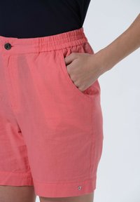 Korallfärgade shorts med elastisk midja, sidfickor och en knapp fram. Tillverkade av lättviktsmaterial med en liten logodetalj.