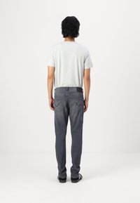 Grå t-skjorte med korte ermer, båret med mørkegrå jeans med baklommer og subtil søm. Svart belte for ekstra støtte.