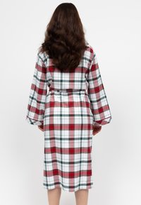 Accappatoio a quadri con un motivo a check bianco, rosso e verde, con maniche lunghe, cintura e design di lunghezza media, realizzato in tessuto morbido.