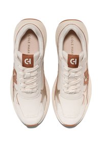 Vita sneakers med bruna accenter, gjorda av läder och tyg, med rundad tå, snörning och subtil märkning på tungan och sidan.