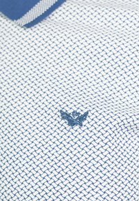 Camisa polo para hombre con un patrón de malla en blanco y marino, que cuenta con un cuello en sólido marino y un logo bordado en marino.