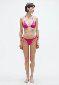 Rózsaszín bikini szett háromszög felsővel és oldalt megkötős, testhez simuló alsóval. Simai textúra, minimalista design, látható minták nélkül.