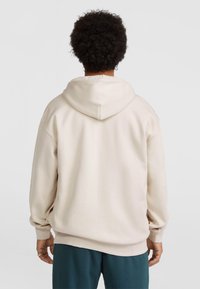 Felpa beige con un ampio cappuccio morbido e spalle basse. Presenta polsini e orlo a coste, realizzata in un mix di cotone testurizzato.