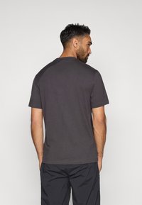 Camiseta cinza escuro de manga curta com decote redondo, textura suave e design simples. Apresenta um corte descontraído e mangas raglan.