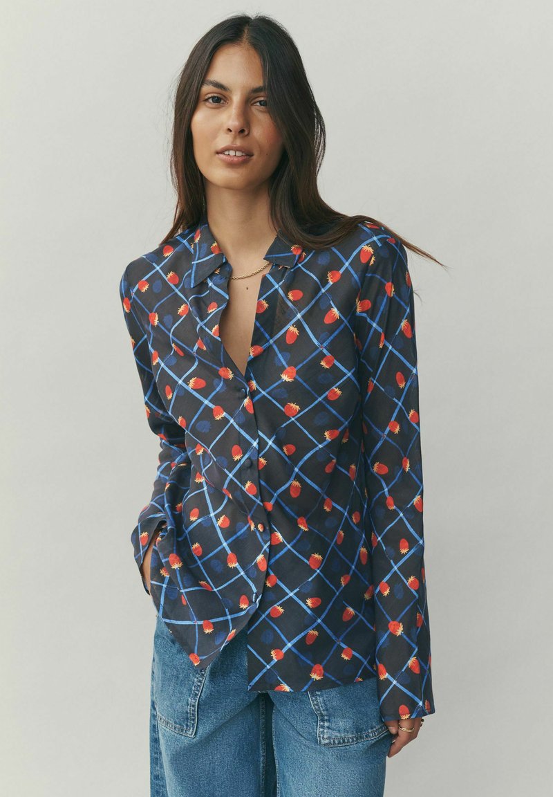 Bluza bleumarin cu un model geometric de flori roșii și linii albastre. Mâneci lungi, partea frontală cu nasturi și o textură moale a țesăturii.