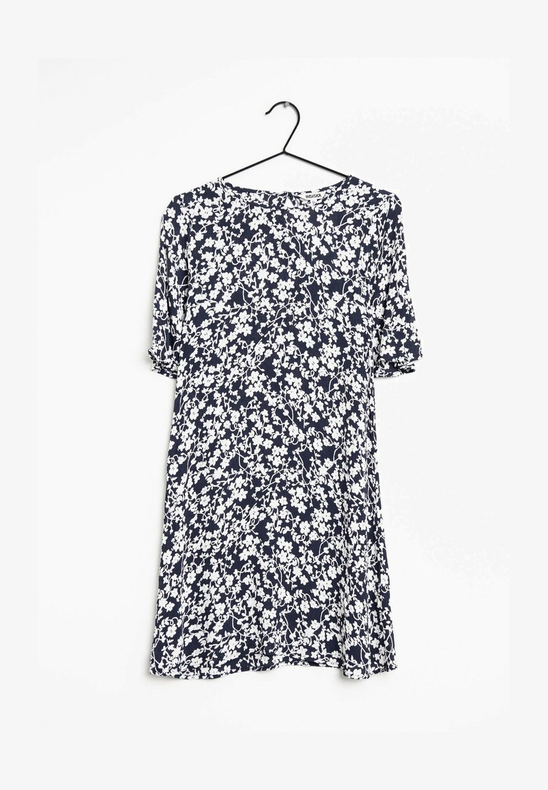 Robe bleu marine à manches courtes avec motif floral blanc suspendue sur un cintre noir sur fond blanc.