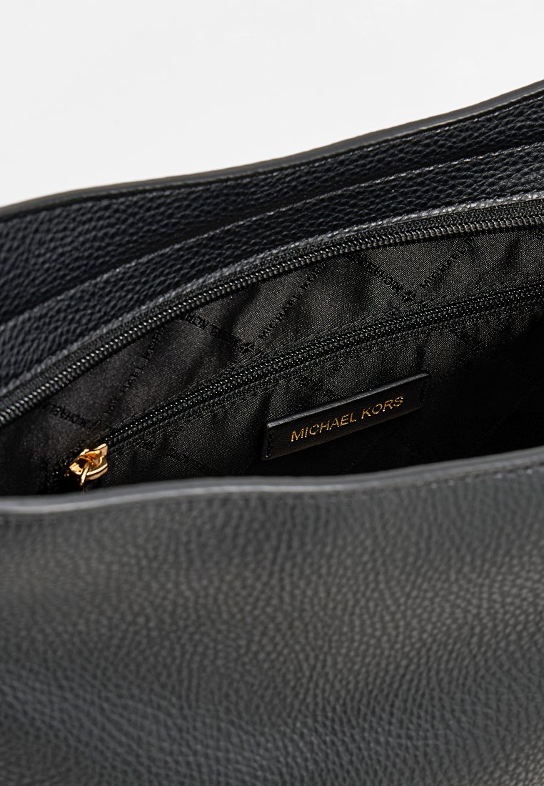 Borsa tote nera in pelle con esterno texture, dotata di chiusura con zip e fodera in satin liscio. Etichetta del logo dorato visibile all'interno.