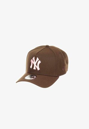 Brown baseball cap with a pink embroidered New York Yankees logo. Features a structured front, curved brim, and fabric adjustable closure.