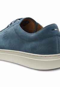 Sneaker in pelle scamosciata blu con suola bianca, design basso, piccole cuciture multicolore sul tallone e fodera interna marrone parzialmente visibile.