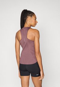 Μωβ αθλητική μπλούζα χωρίς μανίκια με σχεδιασμό racerback, υφασμάτινη υφή και αντίθετο τμήμα από δίχτυ. Συνδυάζεται με μαύρο σορτσάκι που φέρει λογότυπο.