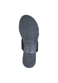 Chaussures noires avec une semelle en caoutchouc texturée présentant un motif hexagonal. La semelle a une conception plate et comporte une étiquette de marque.