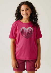 Camiseta magenta de manga corta con un gráfico en forma de corazón que presenta montañas y árboles. Combinada con pantalones cortos magenta a juego.