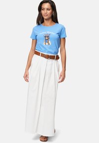 T-shirt bleu à manches courtes avec un graphique "Coffee Monday", associé à une jupe maxi blanche taille haute et une ceinture marron. Baskets visibles.