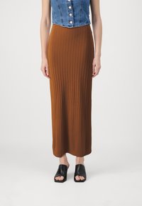 Gonna maxi marrone a coste con vestibilità slim, realizzata in materiale elasticizzato, abbinata a mule nere open-toe. Top in denim con bottoni.