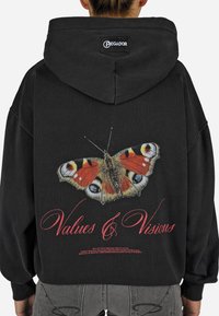 Sweatshirt preto com uma estampa de borboleta nas costas, apresentando detalhes em vermelho e texto branco que diz "Valores & Visões". Ajuste suave e largo.