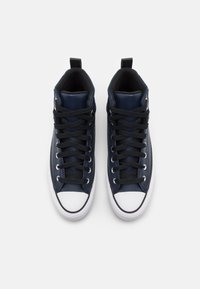 Vysoké tenisky z tmavě modré kůže s černými tkaničkami, bílými gumovými špičkami a texturovanými bočními panely. Disponují poutkem pro snadné nazouvání.