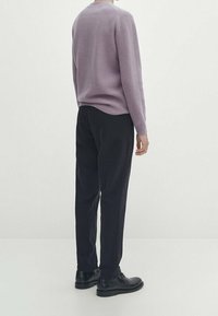 Pull tricoté violet clair, pantalon noir et chaussures noires. Le pull présente un col rond, une finition texturée et une coupe décontractée.