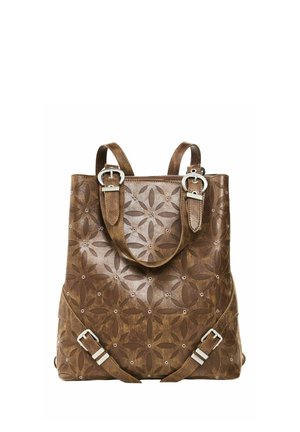 Brauner Leder-Rucksack mit floralen Ausschnittmustern, silbernen Schnallen und doppelten verstellbaren Schultergurten auf weißem Hintergrund.