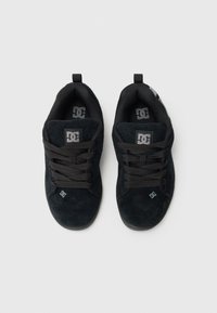 Zwarte suède sneakers met een gestructureerd oppervlak, voorzien van zwarte veters, een gevoerd kraagje en een grijs logo aan de zijkant en op de tong.