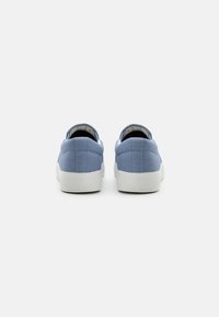 Blue canvas sneakers with white rubber soles, featuring a smooth texture, rounded toe, and minimalist design without visible logos.