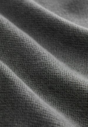 Grijze gebreide stof met een gestructureerd oppervlak, met een patroon van kleine, uniforme steken en subtiele variaties in tint.