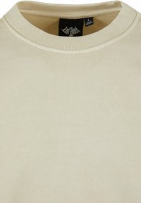 Világos bézs pulóver bordás kerek nyakkal, puha tapintással és lógó címkével a gallér belsejében. Méret: L.