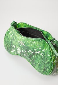 Sac à main vert avec un motif floral en herbe, fermeture éclair, poches intérieures, finition brillante et bandoulière réglable.