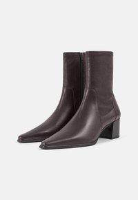 Enkellaarzen van bordeauxrood leer met een puntige neus, zijrits en blokhak. Gladde textuur met een subtiele glans, laag uitgesneden ontwerp.