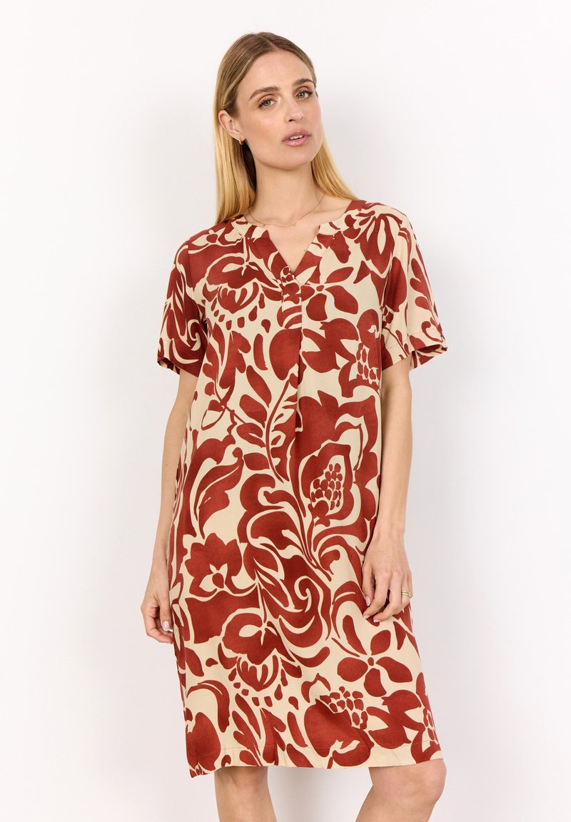 Short, beige dress with a floral pattern in dark red. Features a V-neckline, short sleeves, and a relaxed fit. Smooth fabric texture.