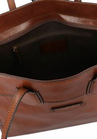 Borsa a mano in pelle marrone con due manici, tasca interna con zip, texture liscia e una sottile placca del marchio su una fodera più scura.