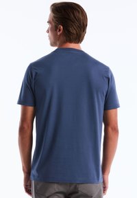 T-shirt à manches courtes, col ras du cou en coton bleu foncé avec une texture lisse. La vue arrière montre des détails de couture et une coupe décontractée.