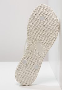 Witte sneakersole met een gestructureerd rubbermateriaal, voorzien van circulaire grippatronen, een voelbare maatmarkering (EUR 36) en twee ronde nopjes.