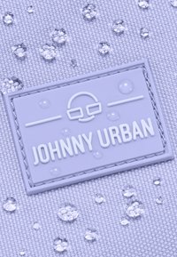 Tissu violet avec des gouttes d'eau et une surface texturée. Présente une étiquette en caoutchouc rectangulaire avec "JOHNNY URBAN" en lettrage blanc en relief.