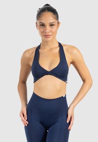 Marinblå sport-bh med djup V-ringning och överlappande design, tillverkad av elastiskt material; i kombination med högmidjade matchande leggings.