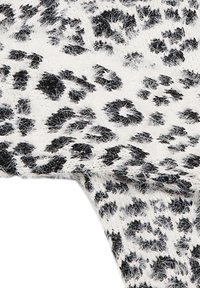 Vit stickad tyg med ett svart leopardmönster, som har en mjuk textur och en fluffig känsla, med tydliga fläckar och former.