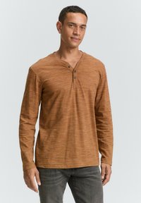 Langermige, roestkleurige henley shirt gemaakt van textuurstof, met een V-hals, drie knopen en een relaxte pasvorm.